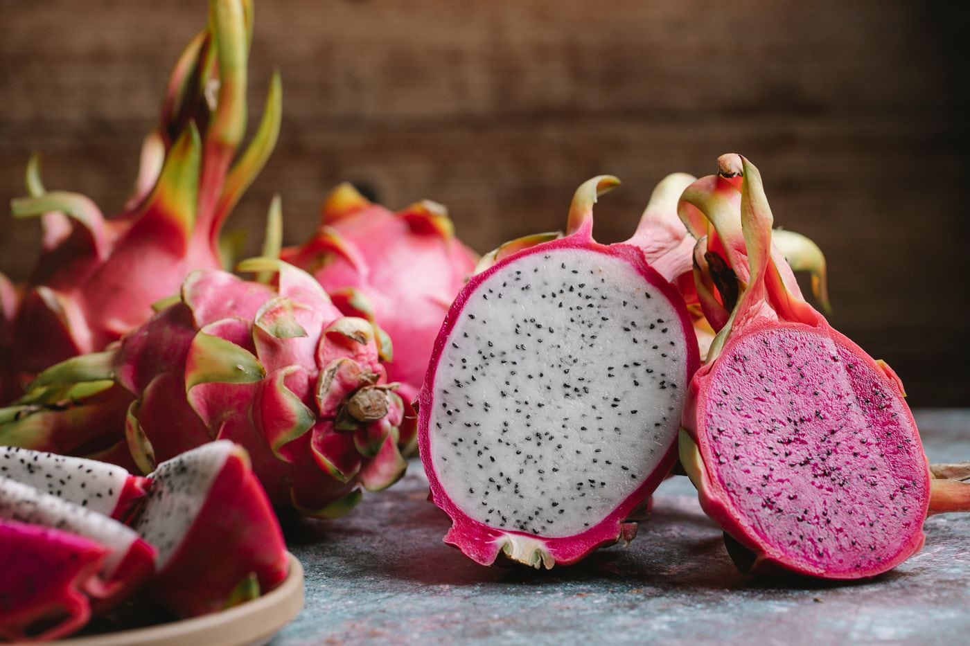 Whole and halved dragon fruits with their pink skin visible.