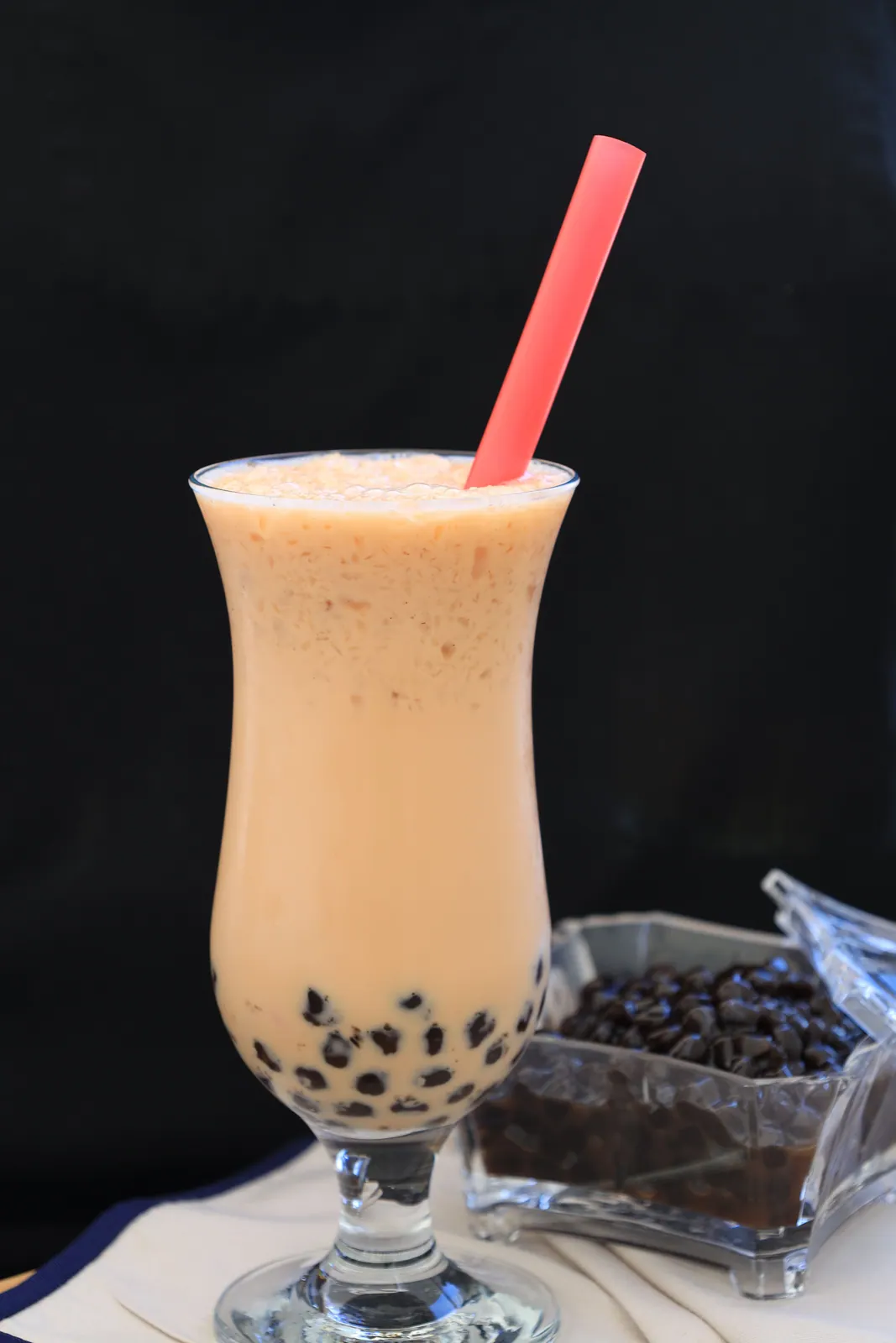 A fruit drink with tapioca pearls and a wide straw