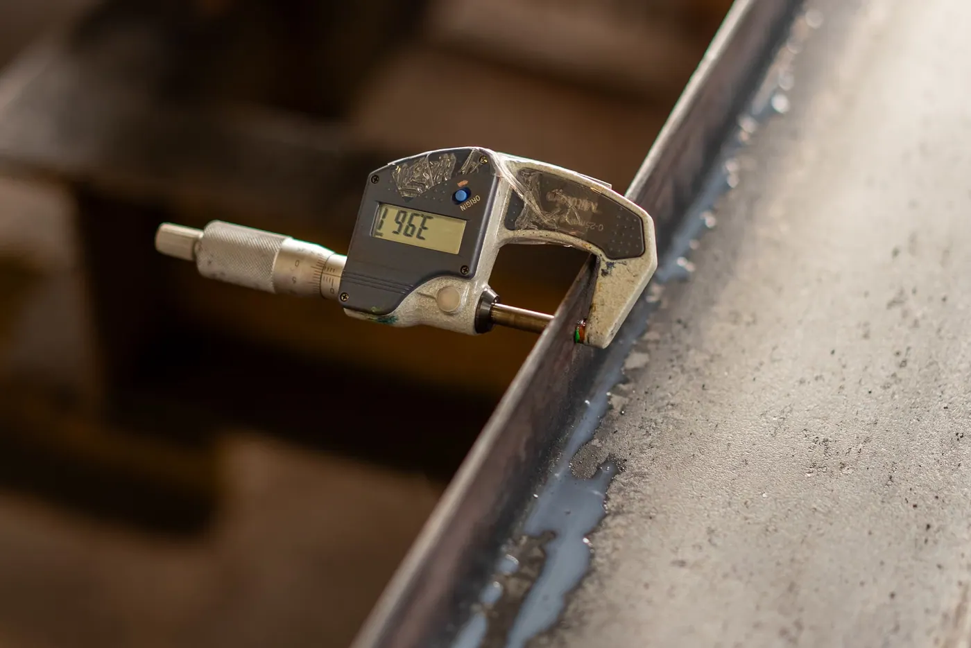 A digital caliper measuring a metal object